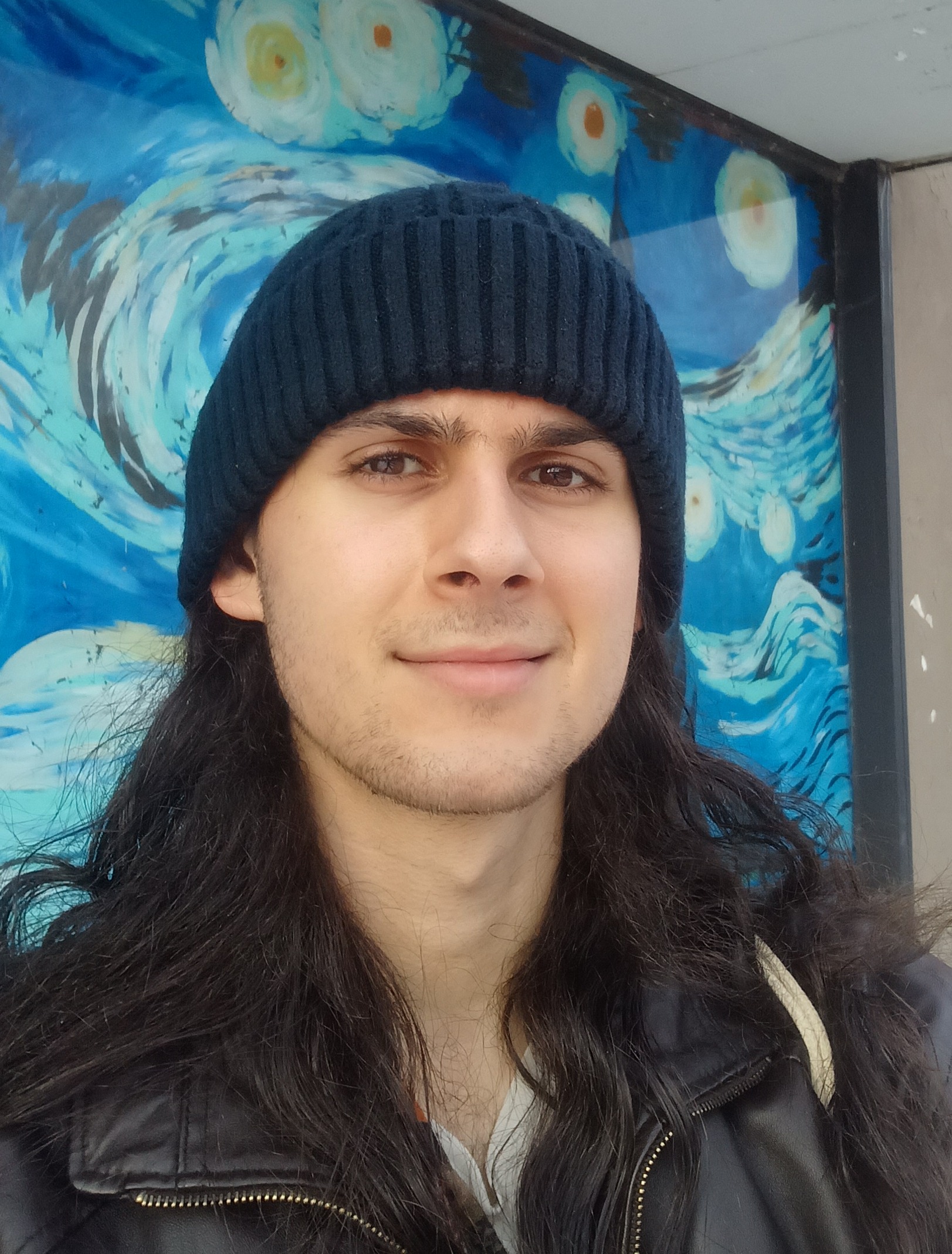 Leon smiling in front of an abstract wave mural